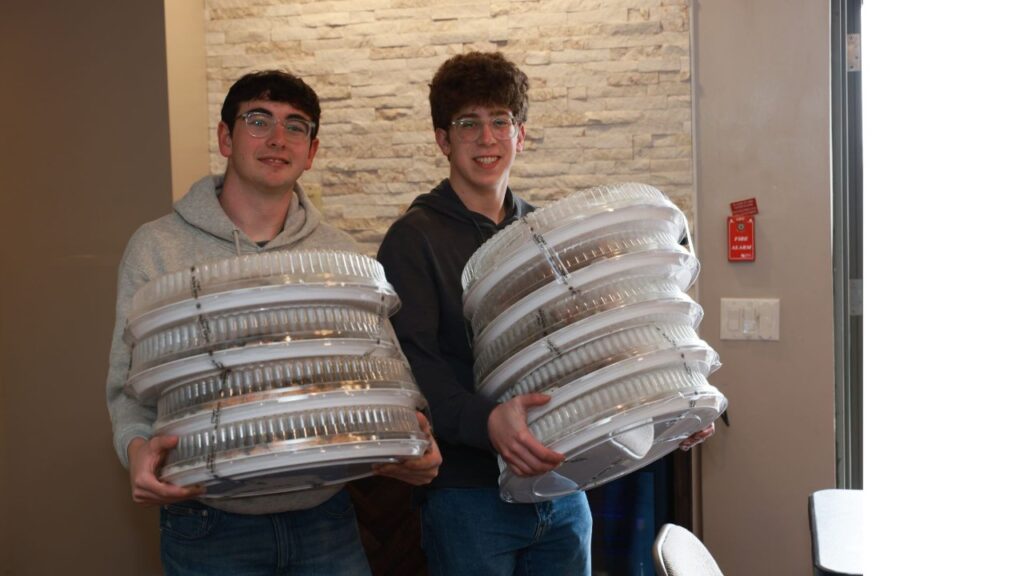 JHP Penn students carrying stacks of food trays for the Shabbat for 1K dinners